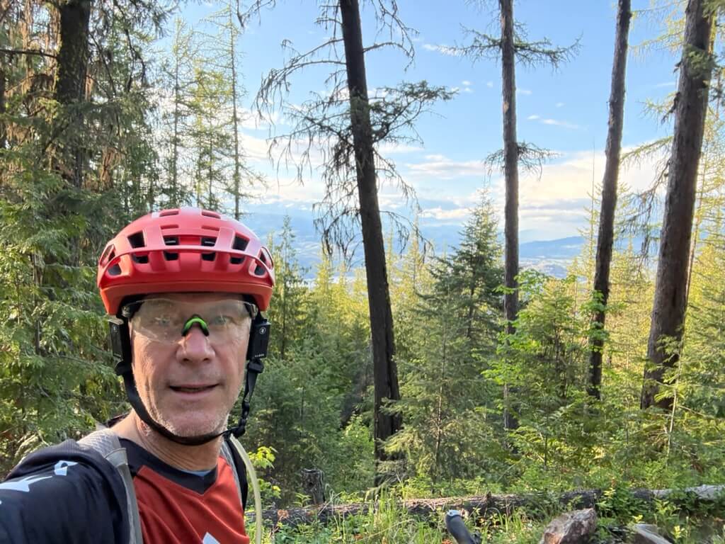 Warren Macdougall in a red mountain bike helmet on a forest trail